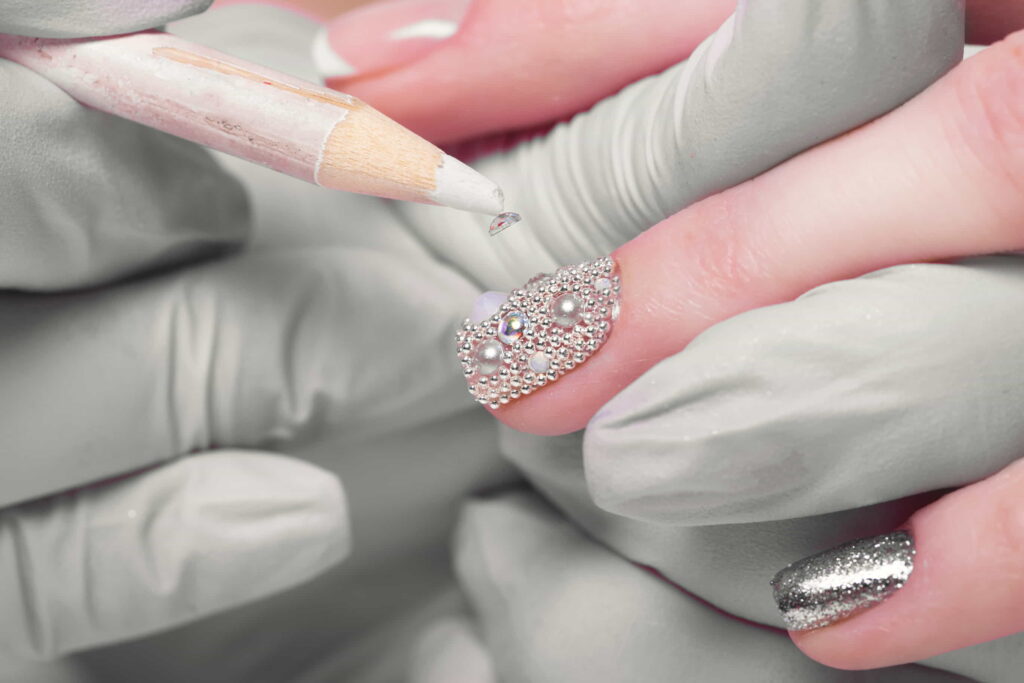 Close-up view of a nail technician's hand, applying an intricate nail art design with precision