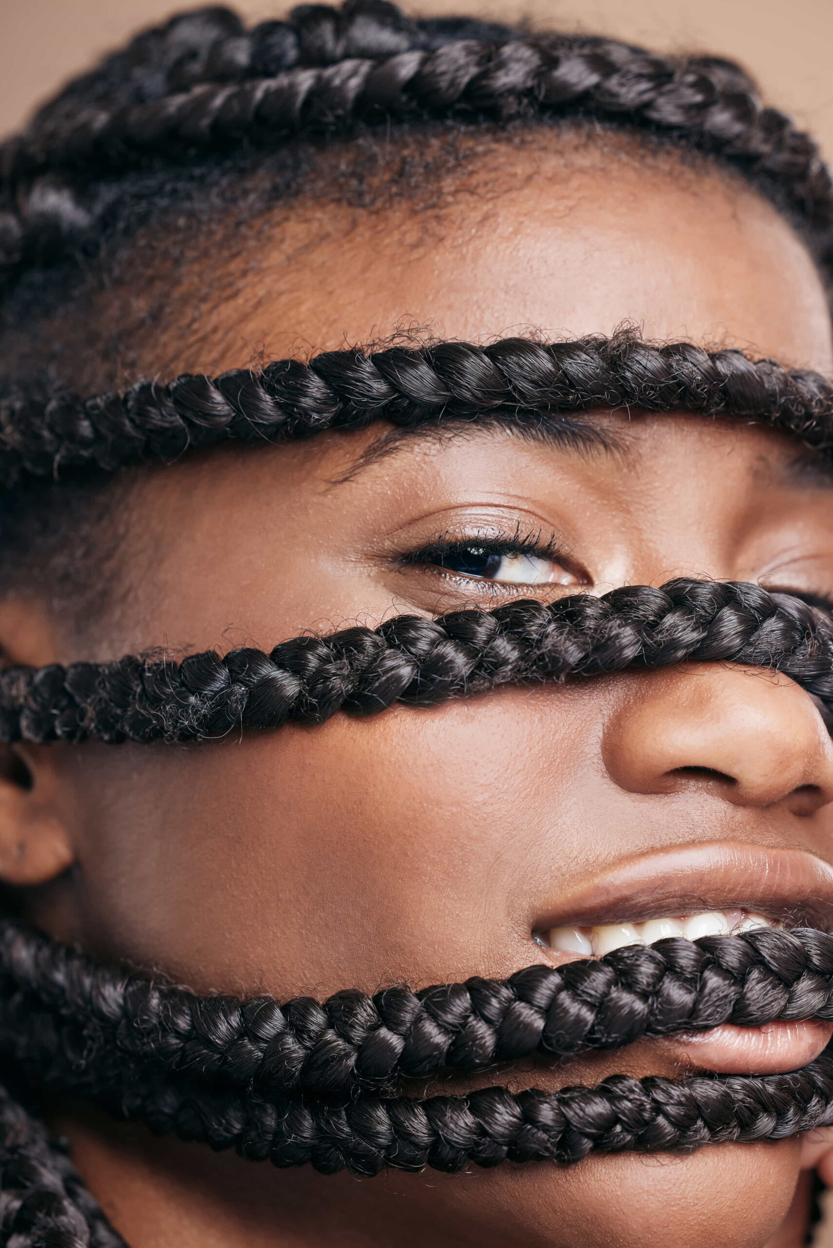 A cropped portrait of a woman posing in a studio, showcasing her braids