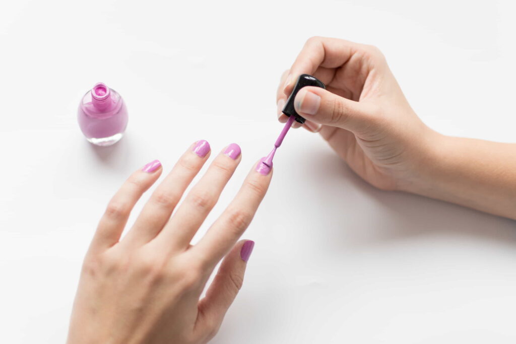 Applying a vibrant nail polish color, showcasing the technique for even layers.