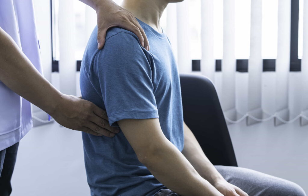 A barber performing a relaxing shoulder and back massage on a client